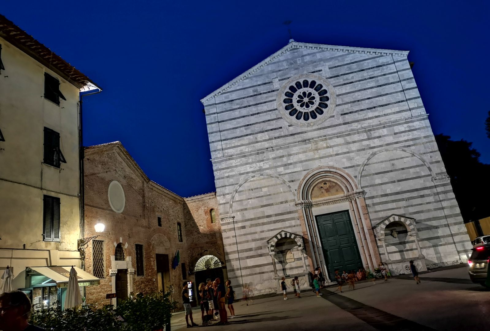 Piazza san Francesco di Notte. sul fondo la facciata semplice della chiesa di San Francesco con tetto a capanna, decorazione a fasce e un rosone nella parte alta.