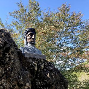 Busto di Dante in pietra, tra la vegetazione