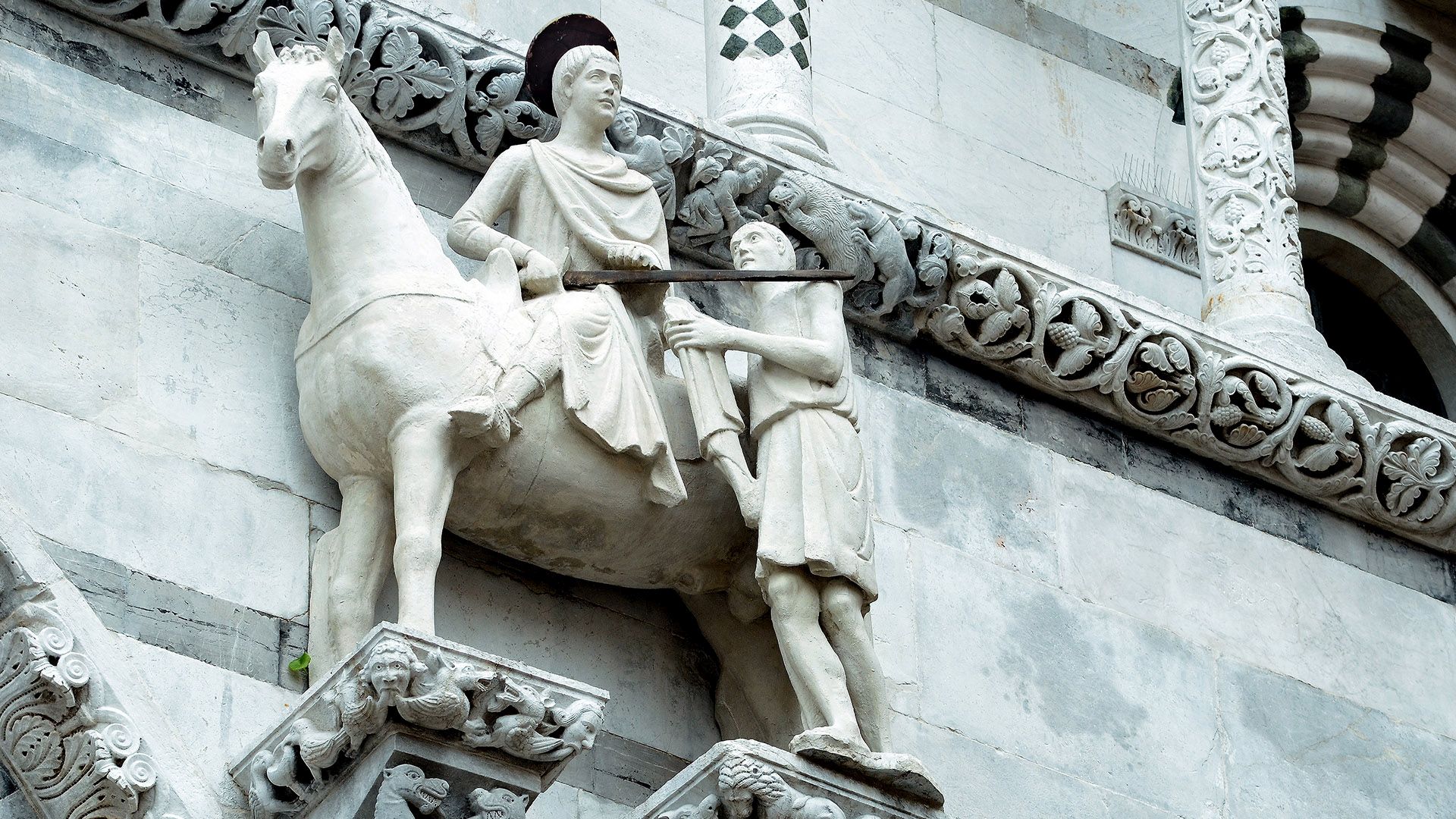 Statua in marmo bianco di San Martino a cavallo che dona il mantello al povero sulla facciata della cattedrale di san Martino di Lucca