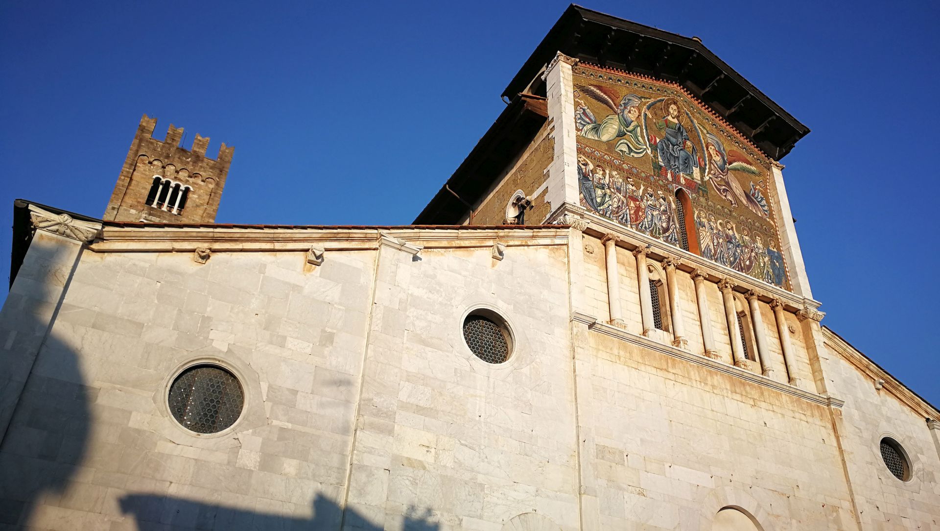 Sulla facciata in marmo bianco della basilica diSan Frediano spicca un grande mosaico in stile bizantino con Cristo in una mandorla affiancato da due angeli e sotto, in riga, i 12 apostoli apostoli