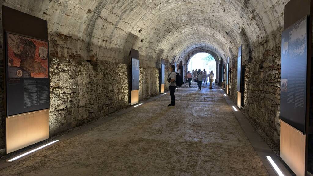 alcune persone guardano i pannelli della mostra Ri-Conoscere le Mura nel sotterraneo del baluardo Santa Croce delle Mura di Lucca
