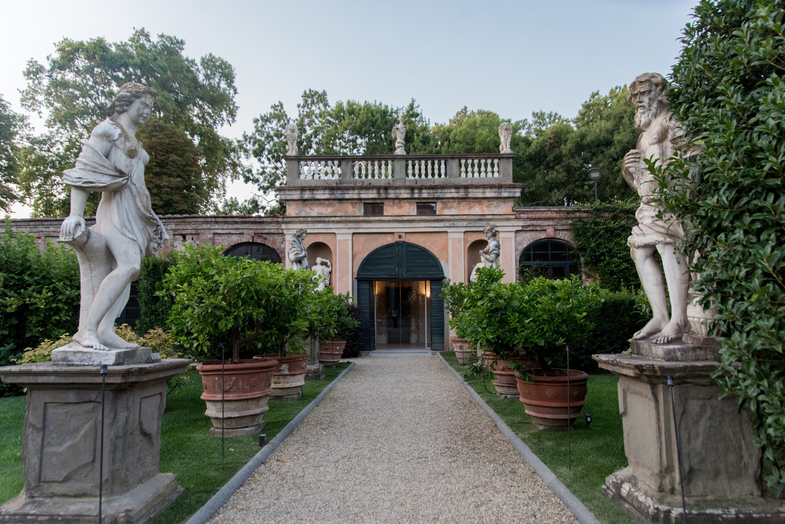 Il viale di statue raffiguranti le stagioni e vasi di limoni del giardino di Palazzo Pfanner si conclude con l'ingresso alle limonaie, sormontate da una balconata con statue di animali