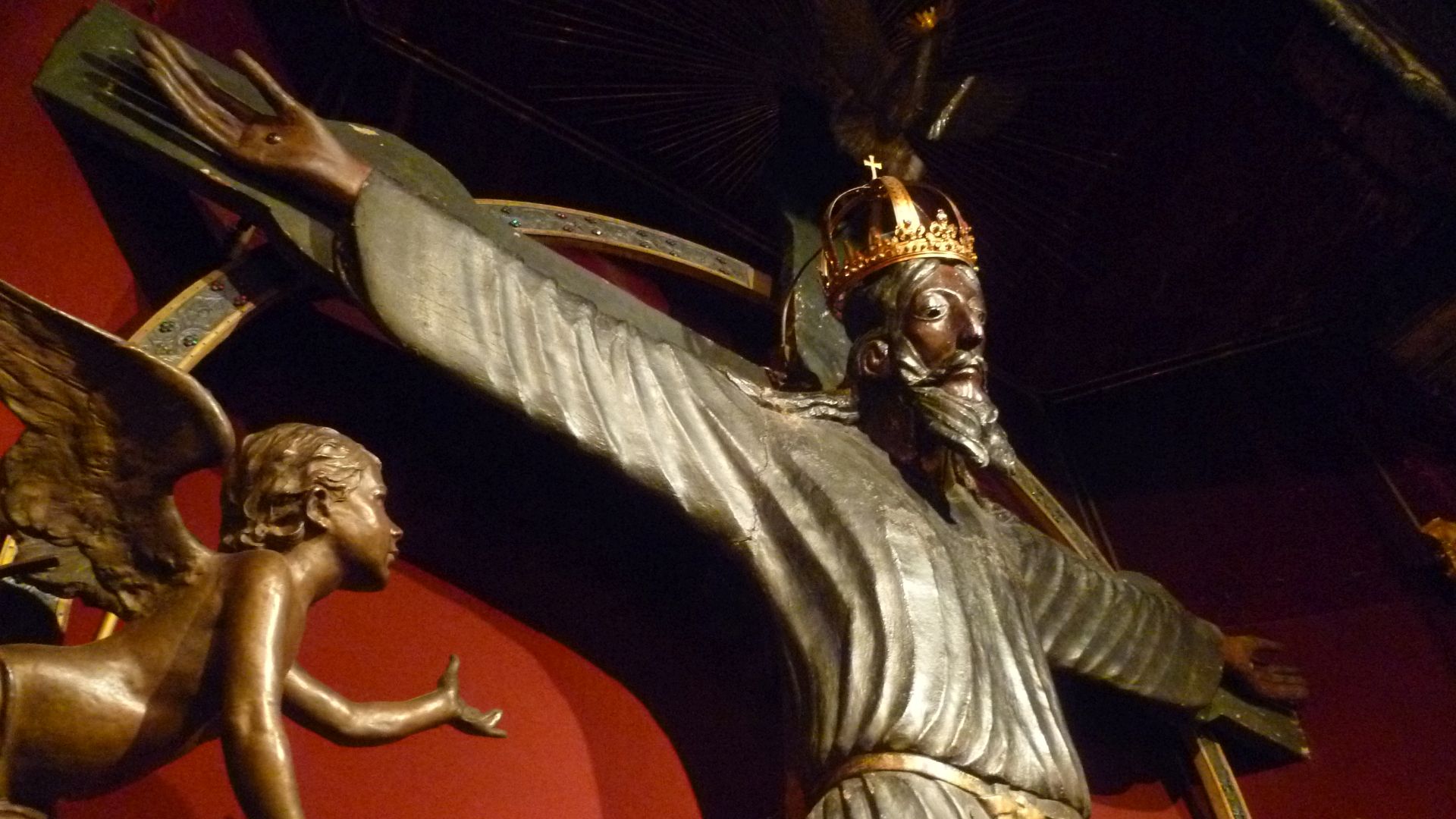 Particolare del busto del volto Santo prima del restauro. UN corcifisso con il volto scuro e i tratti somatici orientali. INdossa una tonaca scura e una corona. Alla sua sinistra un angelo