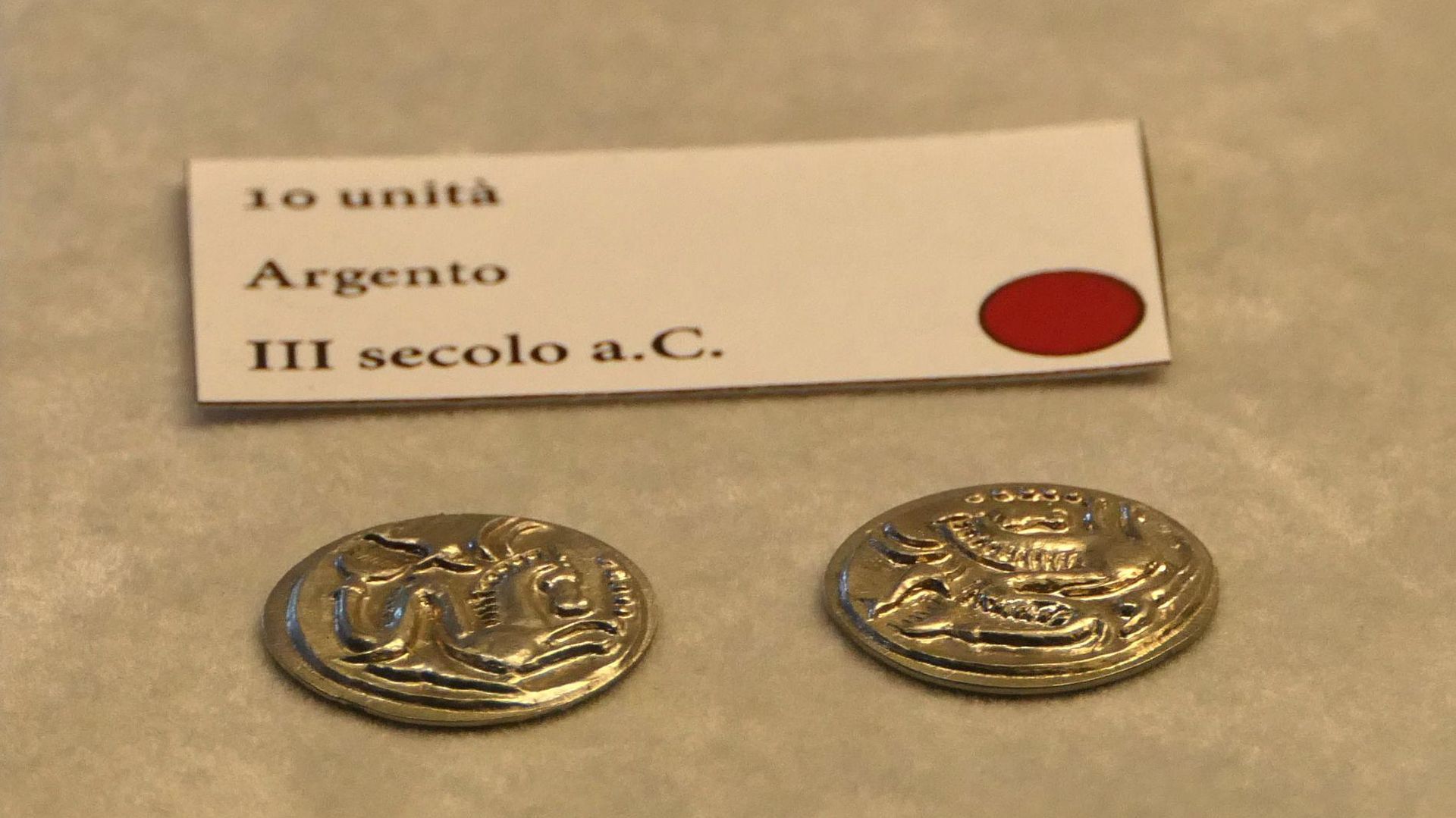 due monete etrusche e un cartellino con scritto 10 unità - Argento - III secolo avanti Cristo. Sulle monete è raffigurato un cavallo marino