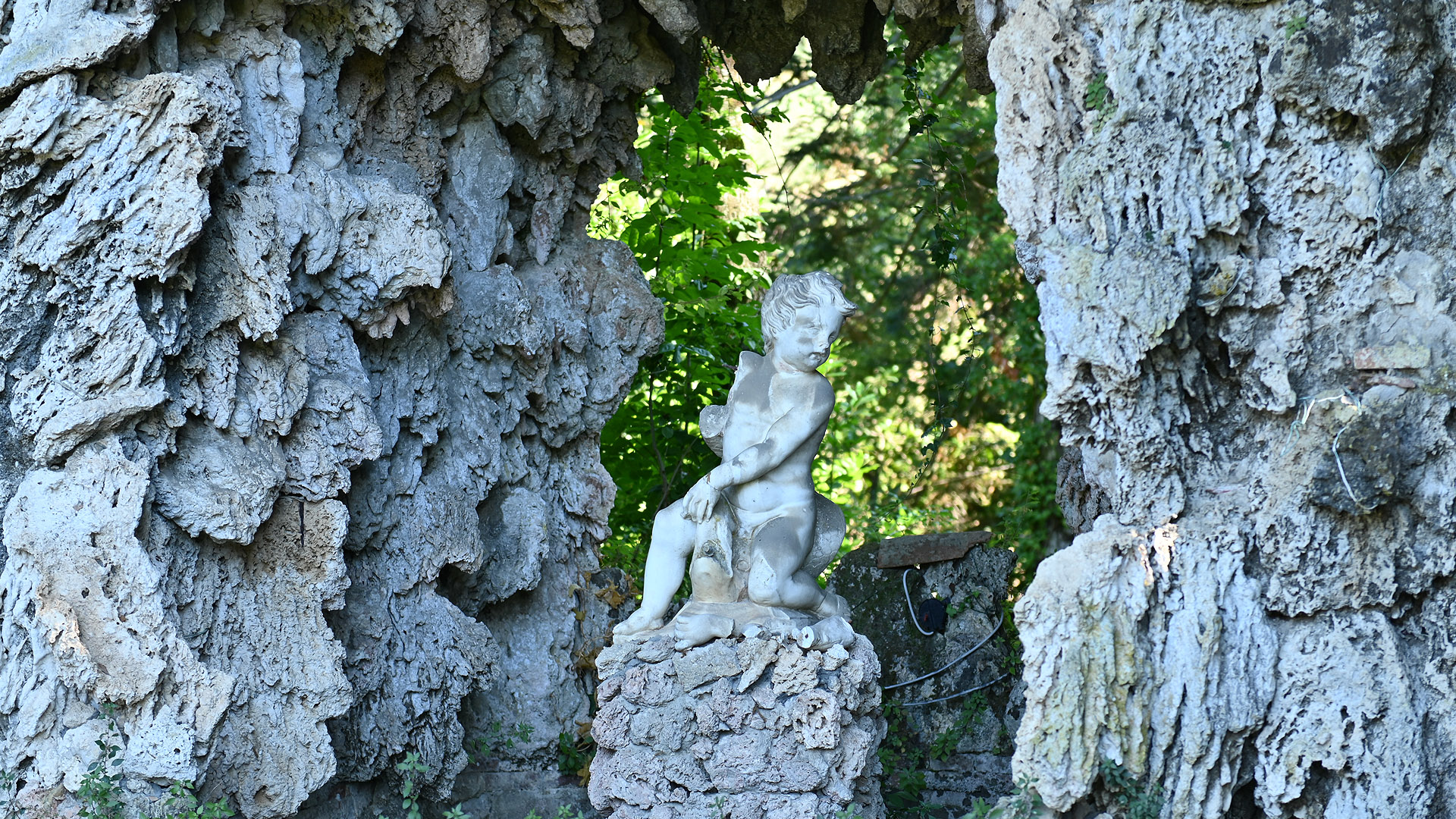 In una piccola grotta artificiale è seduto un putto.