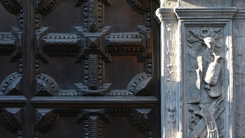 particolare del portone di legno a cassettoni e della cornice in pietra serena scolpita a bassorilievo di palazzo orsetti