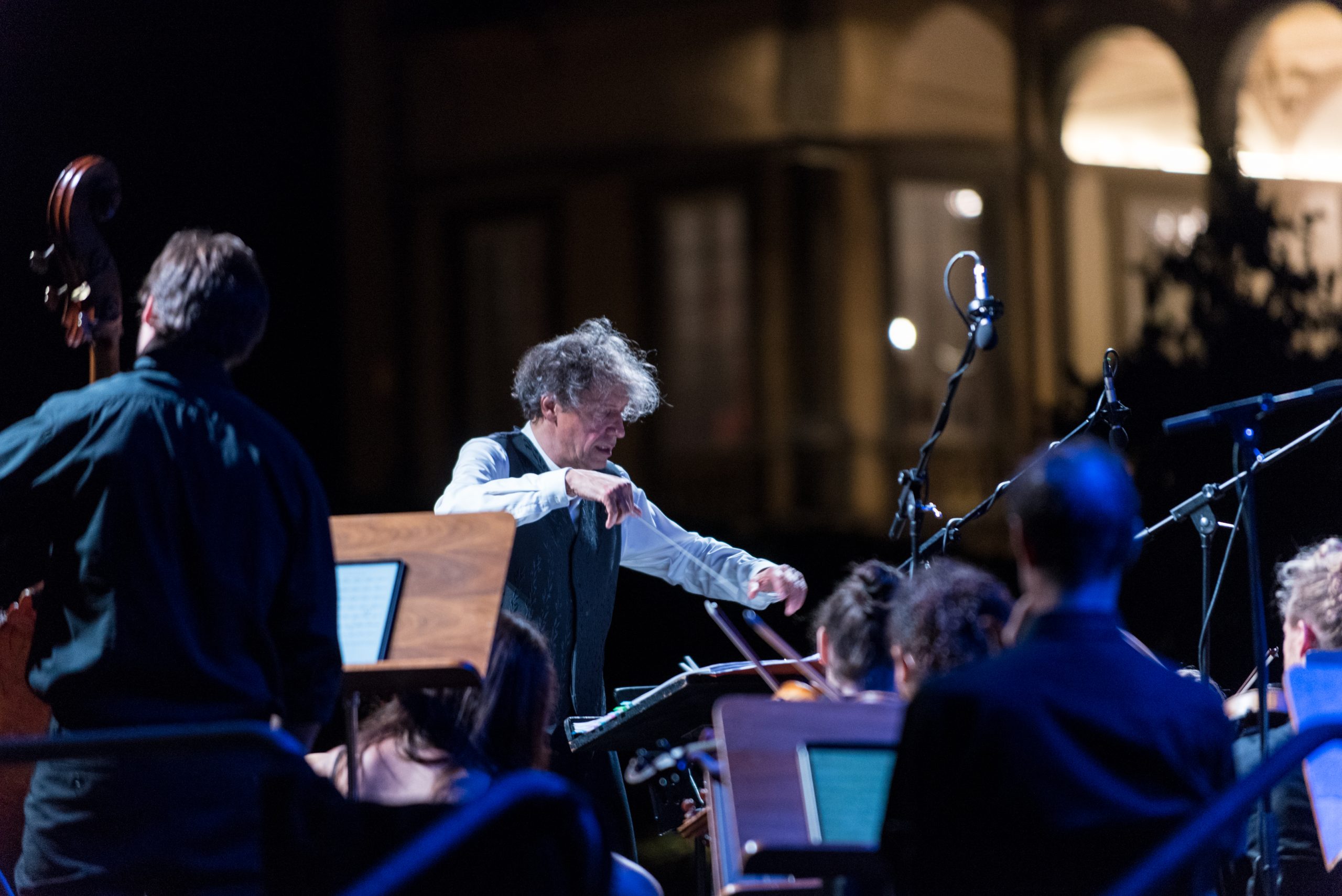 Un concerto in notturna a Palazzo Pfanner che si intravede sullo sfondo.IN primo piano il direttore d'Orchestra e alcuni musicisti con i loro strumenti