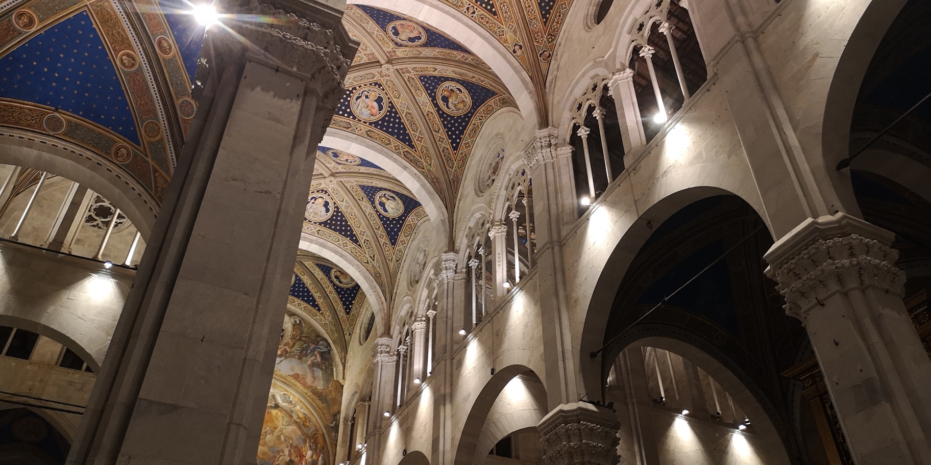 Le alte volte della navata centrale della Cattedrale di San Martino dipinte con cielo stellato. Ai lati il matroneo gotico con trifore e oculi decorati.