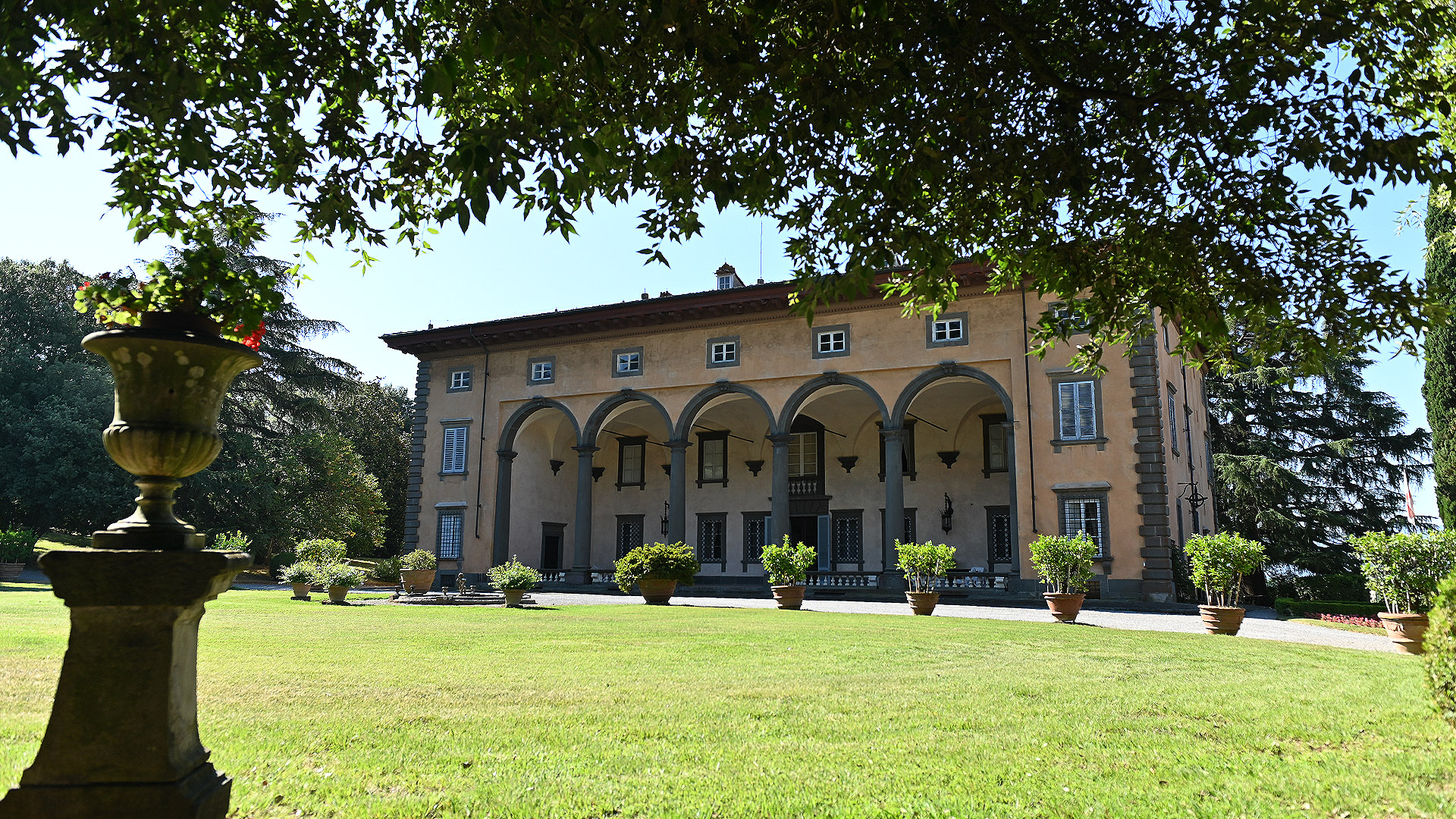 La facciata nord di Villa Oliva, sulle colline lucchesi, vista attraverso le fronde di un leccio. Ha un grande portico a 5 archi che occupa qualsi tutta la facciata