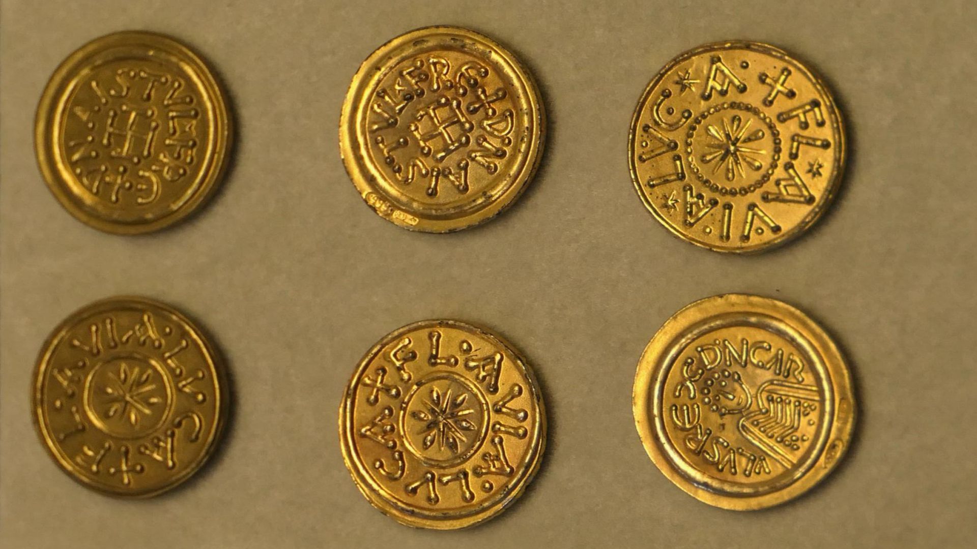 sei monete di epoca medievale al Museo della Zecca di Lucca. Al centro hanno disegni stilizzati di una croce, di un fiore, di una figura umana. Riportano la scritta Lucca Flavia