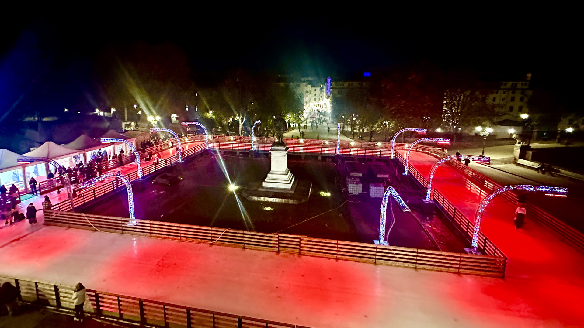 persone alla pista di ghiaccio sulle mura di Lucca. Un eprcorso quadrato intorno alla statua di Garibaldi. Sullo sfondo la città.