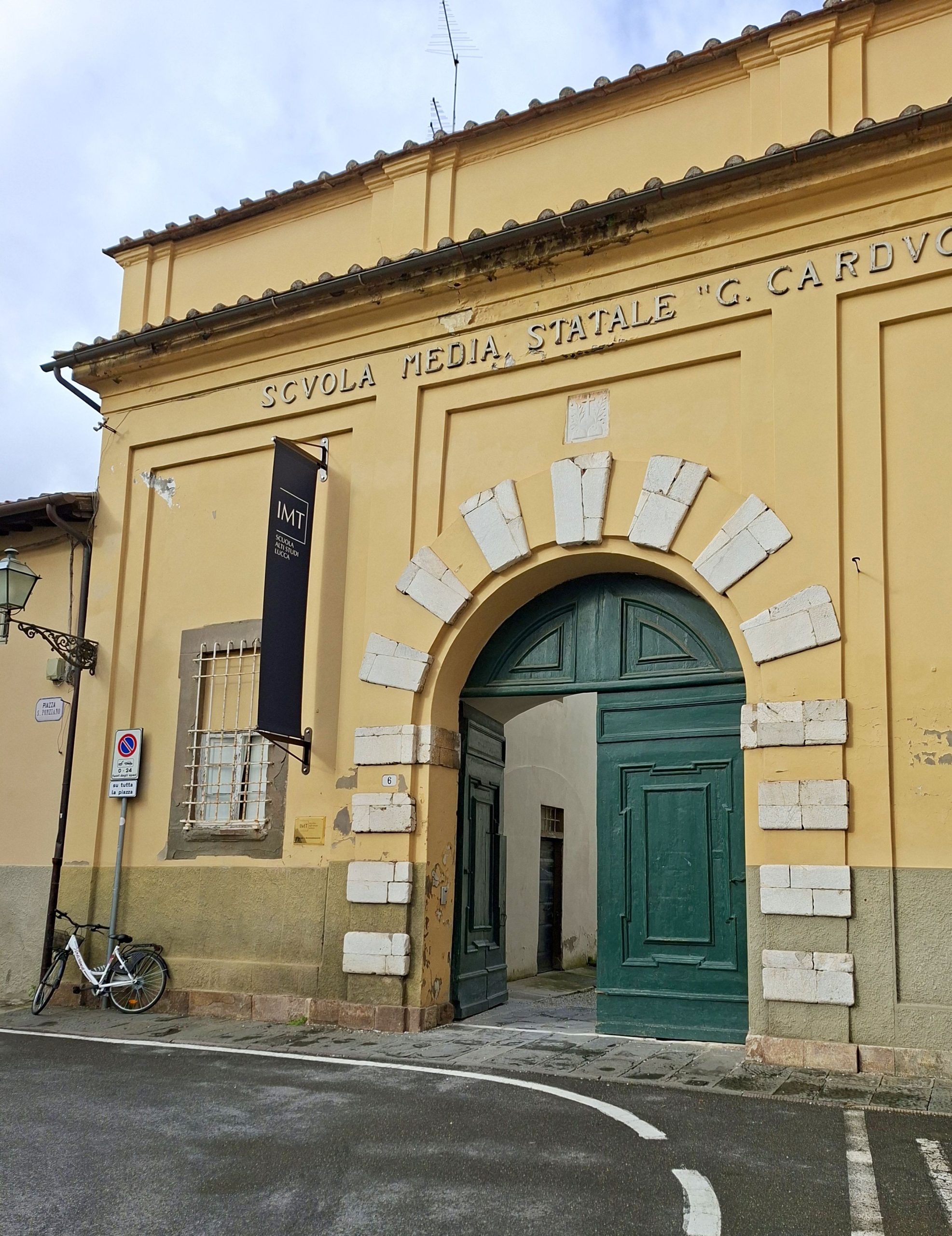 ingresso della scuola media Carducci. Un portone verde contornato da bugnato di marmo alternato a intonaco si apre su un cortile.