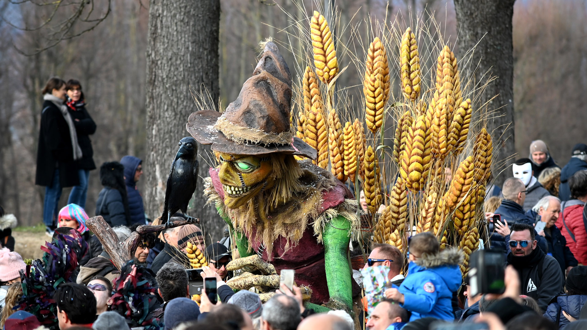 un carro di carnevale don uno spaventapasseri seduto su mazzi di spighe di grano sfila tra la folla sulle mura di lucca