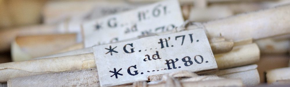 primo piano di alcune pergamene antiche arrotolate con una targhetta