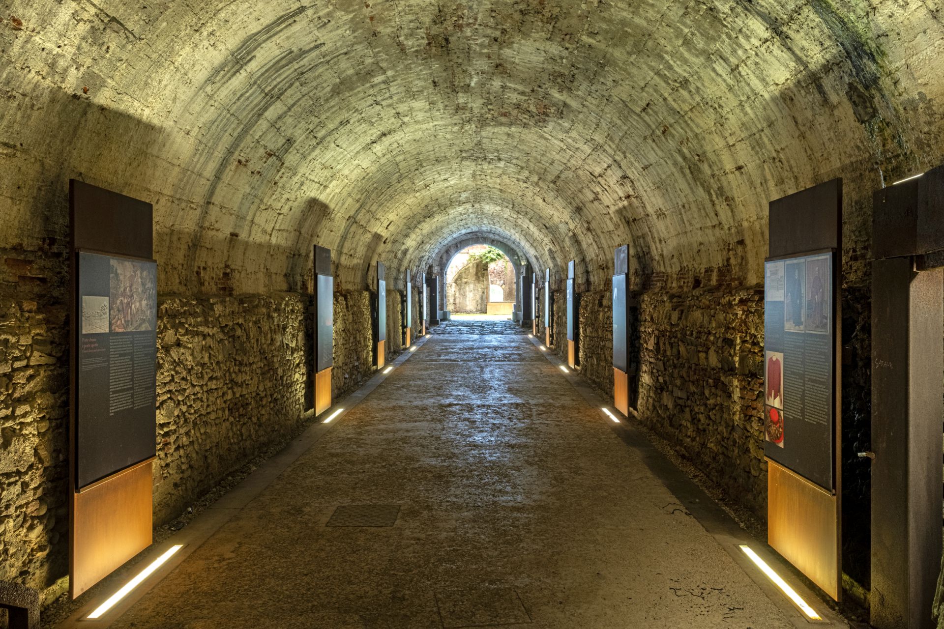 galleria in pietra nei sotterranei delle mura di lucca con allestimento museale.