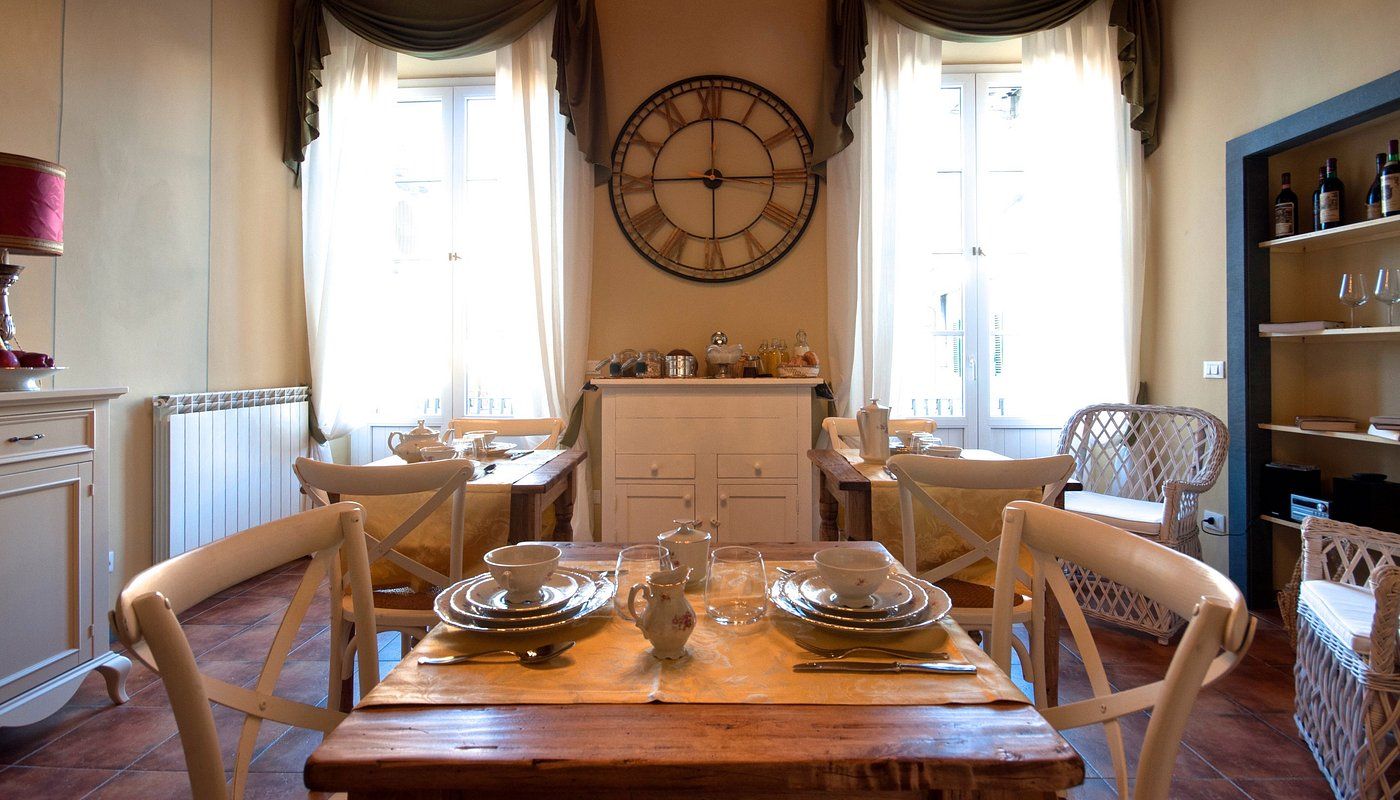 soggiorno del bb corte toro. Un tavolo apparecchiato, due grandi finestre e un orologio da parete