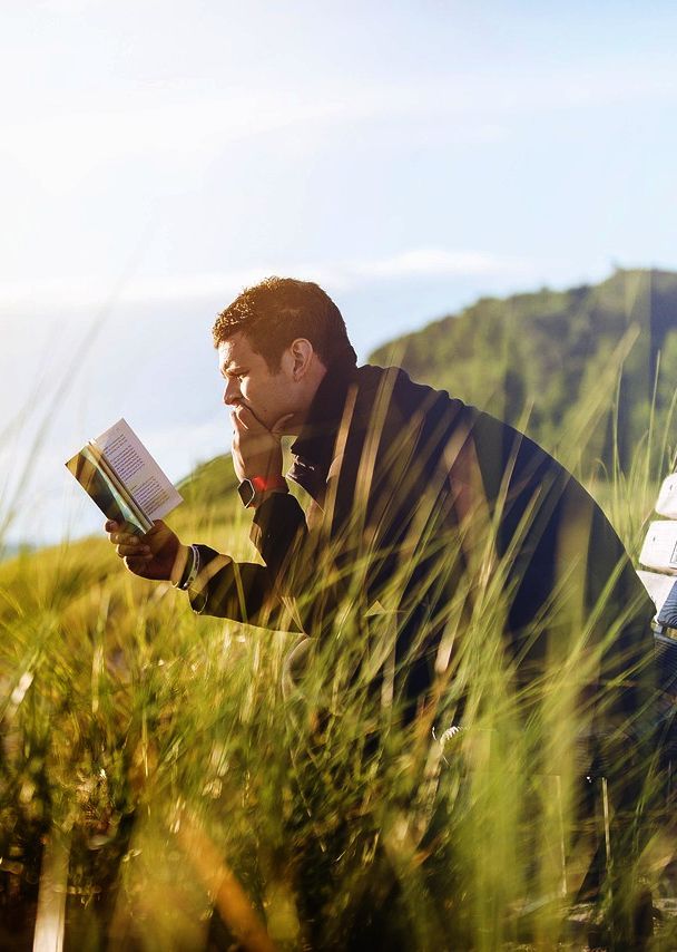 un uomo legge un libro in un posto all'aperto, su una panchina.